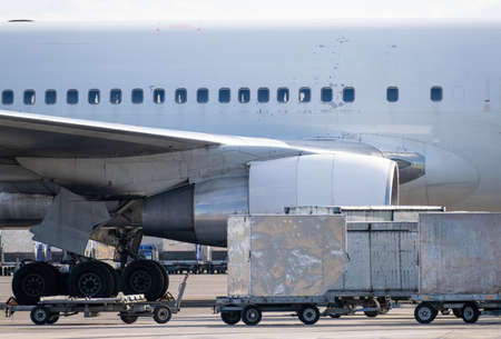 Cargo containers near the passenger planeの写真素材