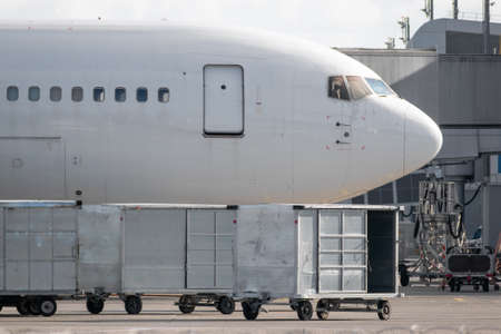 Cargo containers with luggage near the plane on apronの写真素材