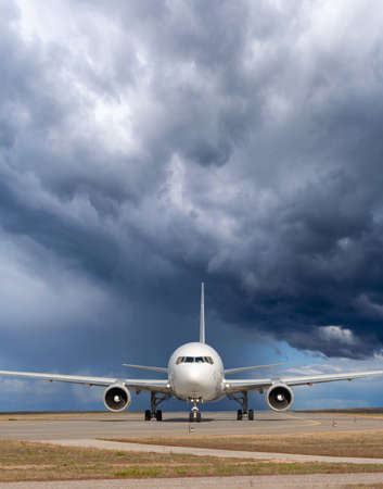 Passenger jet plane on the runway in the airport with the storm on the backgroundの写真素材