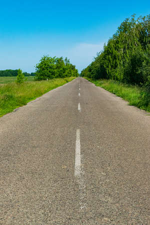 Lanscape with an empty asphalt country road with vivid colorsの写真素材