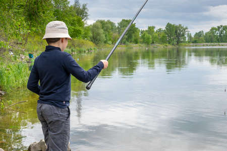 Boy catching fish on the river on a cloudy dayの写真素材