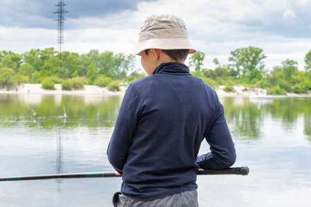 Boy catching fish on the river on a cloudy dayの写真素材