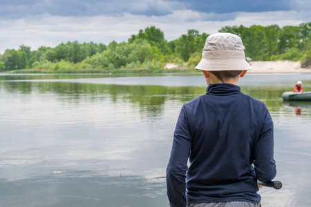Boy catching fish on the river on a cloudy dayの写真素材