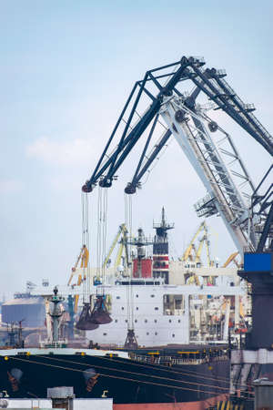 Cranes at the cargo sea port loading the bulk carrier with iron ore or coalの写真素材