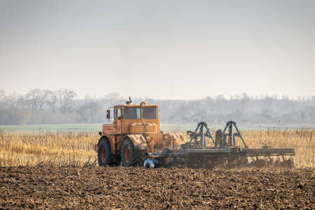 Tractor cultivating the field with harrowの写真素材