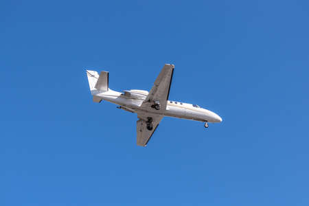 Business jet landing against clear skyの写真素材