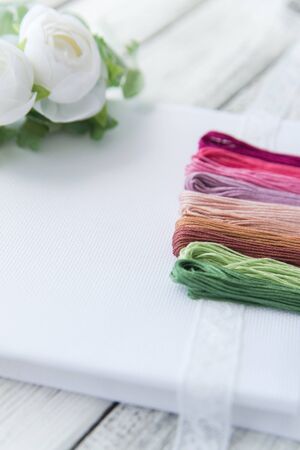 Materials for crosstitching on white wooden background, selective focus, rustic style