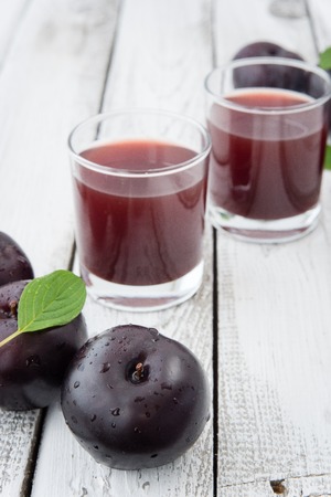fresh plums juice on a white wood background, rustic style, selective focusの写真素材
