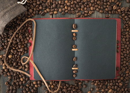 A bag of roasted arabica coffee beans and a dark paper note on a black wooden background top viewの写真素材