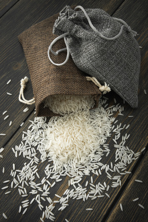 Raw Basmati rice in small jute bags on dark wooden background top viewの写真素材