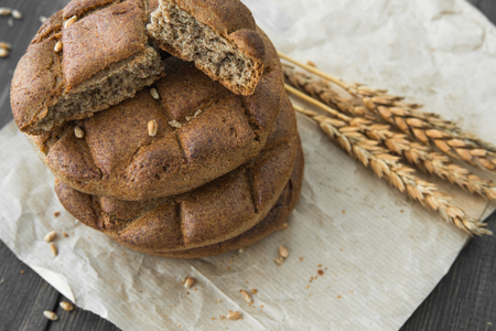 A stack of round rye flatbread buns with rye spikelets on a craft wrapping paper background