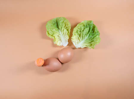 Minimal abstract modern composition of Easter eggs and vegetables on orange background, representing...
