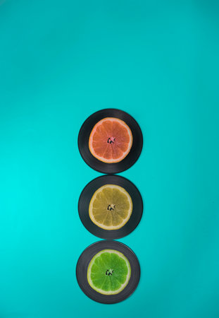 Traffic lights made of fruits and LP records. Turquoise background. Lemon, lime, grapefruit. Minimal traffic and food concept.の写真素材