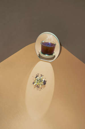 Optical illusion of hot cup of tea and ingredients reflection in the mirror. Two soft trendy colors background. Minimal hot beverage concept.の写真素材
