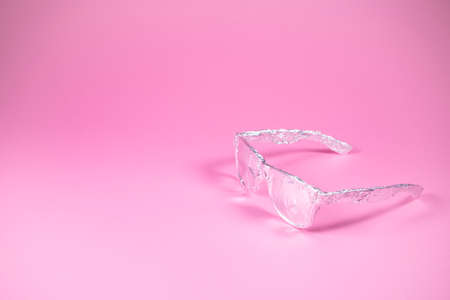 Retro sunglasses wrapped in aluminium foil on trendy pink background. Futuristic look. Minimal...