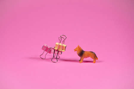 Two dogs on trendy pink background. Kids toy dog and dog made of steel binder clips. Futuristic looking toy. Friends idea. Minimal abstract playing concept.の写真素材