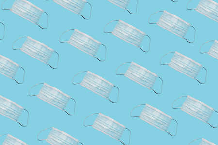 Protective surgical mask on trendy pastel blue background. Minimal pandemic concept. Stay safe.の写真素材
