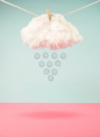 Raining balloons from cloud hanging on a rope. On trendy pastel blue and pink background. Minimal abstract summer and party concept.の写真素材