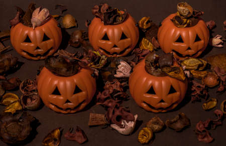 Flat lay layout of dry oranges, peach, nut, hazelnut and flowers spilling from Halloween pumpkins. On pastel brown background. Halloween idea. Minimal season specific and autumn and winter concept.の写真素材