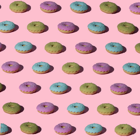 Green, blue and pink donuts layout on trendy pastel pink background. Seamless pattern. Top view. Minimal food and summer concept.の写真素材