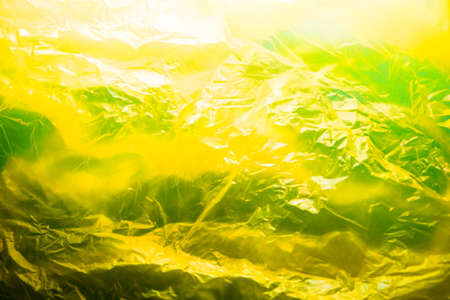 Abstract background made of yellow plastic bag and back lit flash light. Grunge texture. Vibrant colors. Minimal abstract background and pollution concept. With copy space.の写真素材