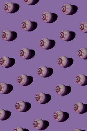Creative layout made of creepy eyeballs on violet background. Flat lay, top view. Minimal abstract Halloween concept. Copy space.の写真素材