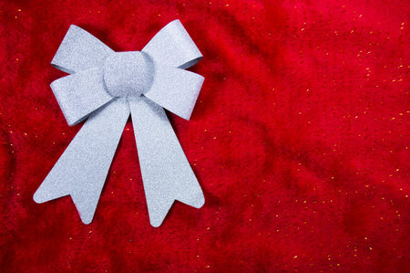Christmas background made of bow ribbon decoration and red furr with golden glitters. Flat lay, top...