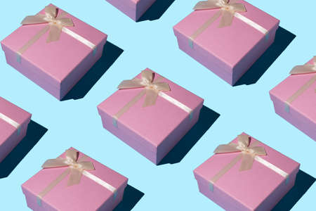 Pink gift box pattern on snowy blue background. Flat lay, top view. Winter holidays idea. Minimal Christmas and New Year celebration concept. With copy space.の写真素材