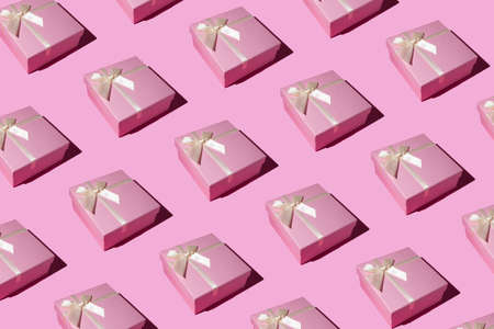 Pink gift box pattern on pastel pink background. Flat lay, top view. Winter holidays idea. Minimal Christmas and New Year celebration concept.の写真素材