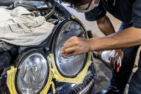 A mechanic polishes the headlights of a car.の写真素材