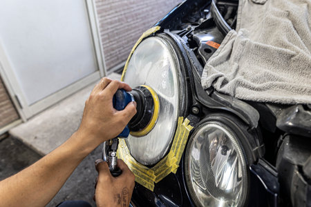 A mechanic polishes the headlights of a car.