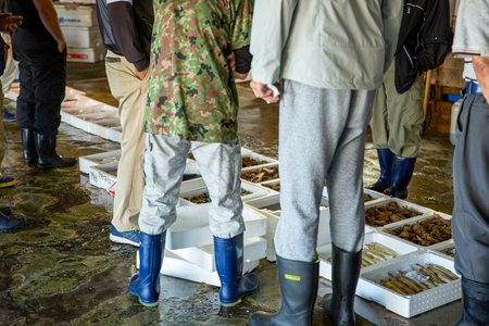 Fishermen in rubber boots preparing fish for sale in fish marketの写真素材