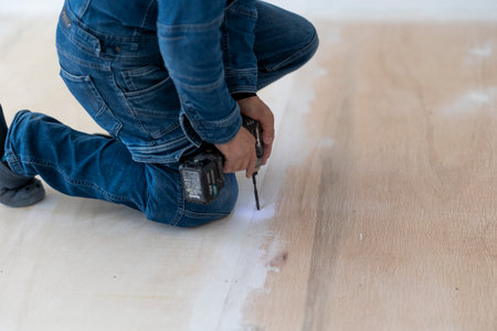 close up of a young man installing laminate flooring at homeの写真素材