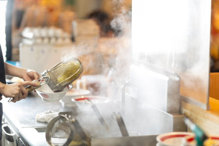Close up of woman cooking food in kitchen at restaurant or hotel.の写真素材