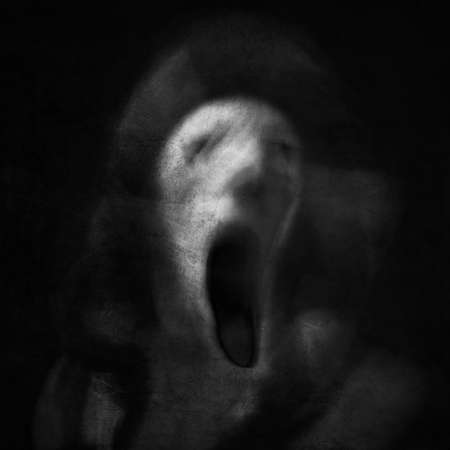 Scream of horror. Screaming ghost face. Scary halloween mask. Shot with long exposure.の写真素材