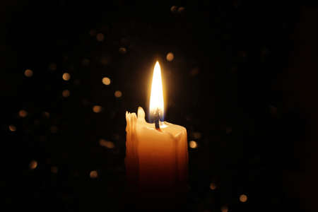 White candles burning in the dark with focus on a single candle in the foreground.の写真素材