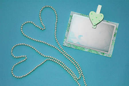 Two hearts of pearl necklaces and pin with old photo frame on blue background. Invitation to your celebration, Wedding card, Valentine's day card, Greeting card.の写真素材