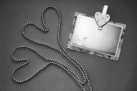 Two hearts of pearl necklaces and pin with old photo frame on black background. Invitation to your celebration, Wedding card, Valentine's day card, Greeting card.の写真素材