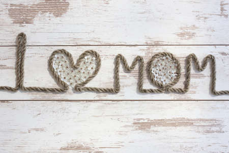 I love Mom. Composition on Mother's Day. Rope text with flower and blossoms on the wooden table, closeup.の写真素材