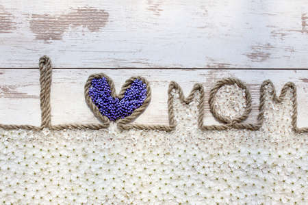 I love Mom. Composition on Mother's Day. Rope text with flower and blossoms on the wooden table, closeup.の写真素材