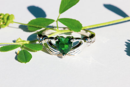 Claddagh ring with green emerald. Traditional Irish ring in shape of two hands holding a heart shaped green gemstone. Symbol of love, loyalty and friendship.の写真素材