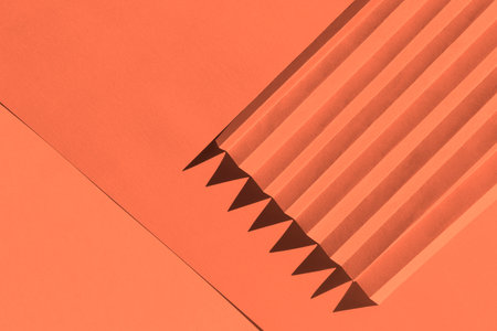 Apricot crush color of the year 2024. Folded paper with harsh sun shadows, geometric shapes and lines 3D texture.の写真素材