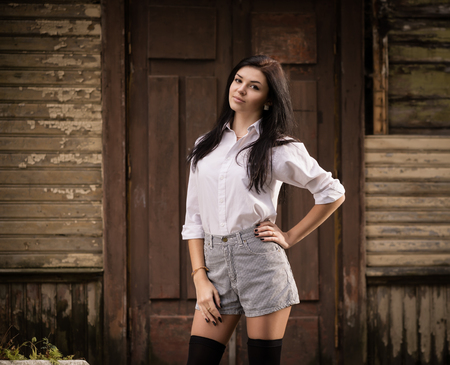 Fashion pretty young woman posing outdoor near a old wooden wall  Beautiful brunette with sensual lips の写真素材