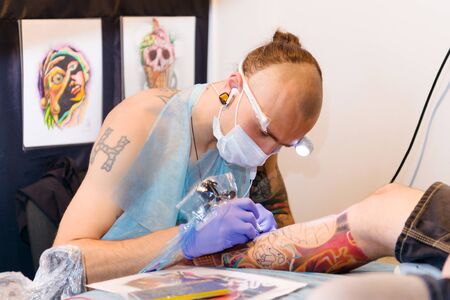 MINSK, BELARUS - SEPTEMBER 19, 2015: Professional tattoo artist doing tattoo on client leg. The 2th International Tattoo Conventionのeditorial素材