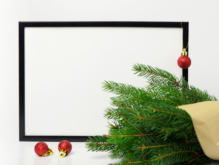 Christmas composition. Black frame and  branches christmas tree, red balls on white background. Front view, mock up, copy space, square, flat lay, for congratulations

の写真素材
