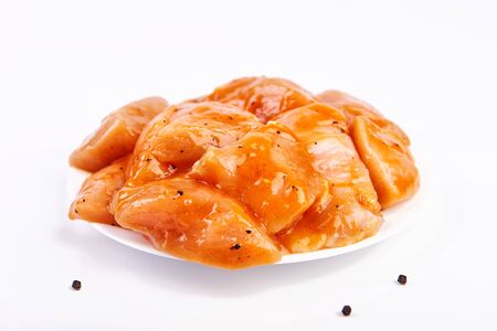 raw meat marinated in spicy sauce close-up, isolated on white background with slices pepperの写真素材