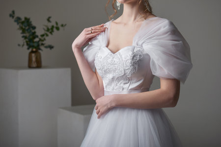 A beautiful young bride model in long lace dress in minimalist white studio interior. Wedding photography.の写真素材