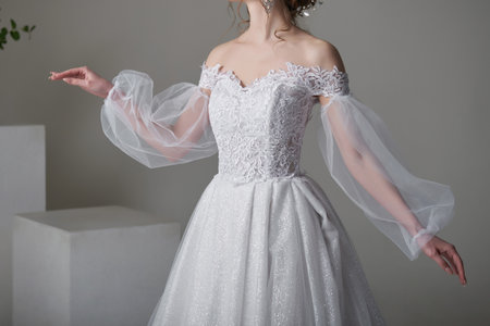 A beautiful young bride model in long lace dress in minimalist white studio interior. Wedding photography.の写真素材