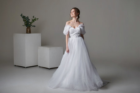 A beautiful young bride model in long lace dress in minimalist white studio interior. Wedding photography.の写真素材