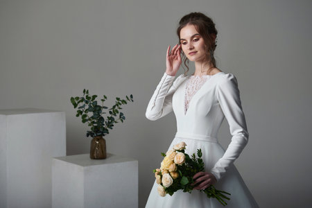 A beautiful young bride model in long lace dress in minimalist white studio interior. Wedding photography.の写真素材